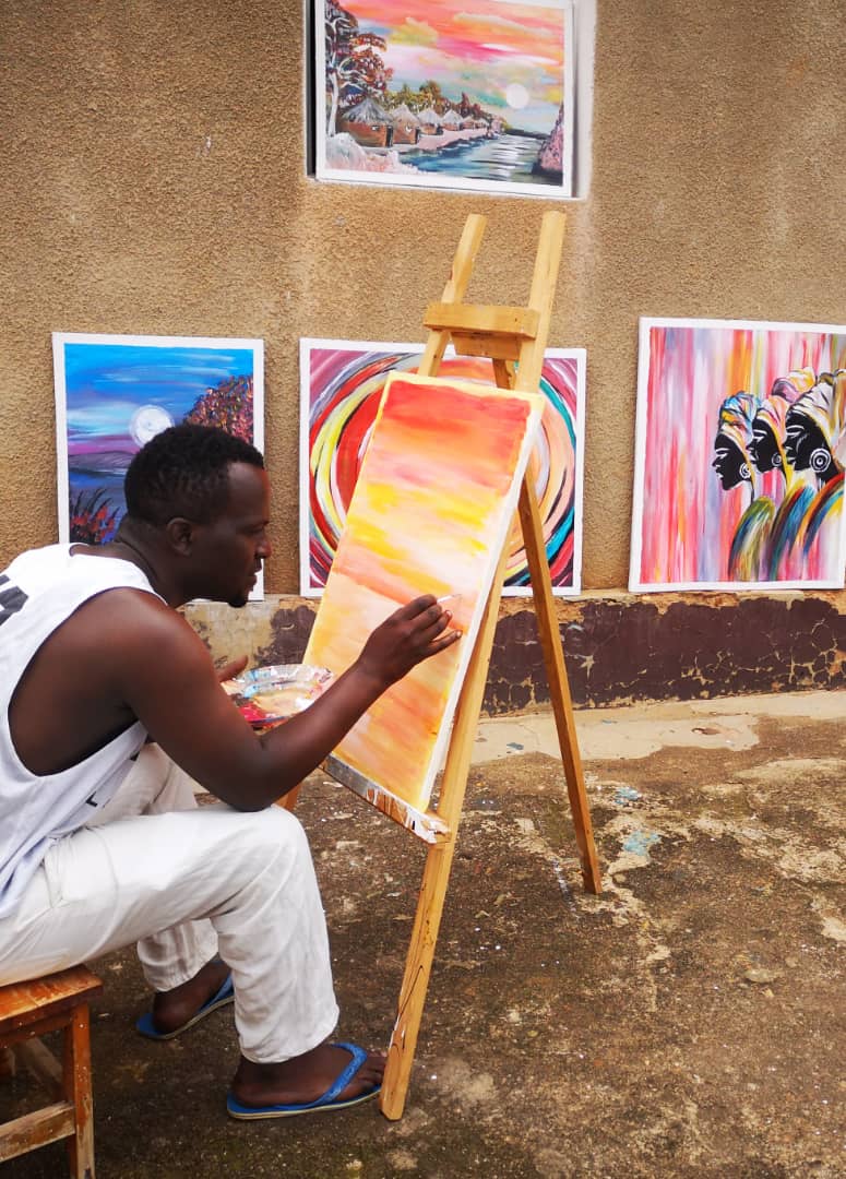 Ivan Mapike painting outside his room in Rwanda